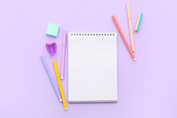 Skład z pustym notebookiem i materiałami szkolnymi na tle liliowym - Zdjęcie, obraz