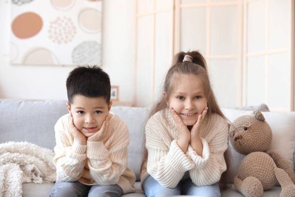 Cute małe dzieci w dzianiny swetry siedzi na kanapie w domu - Zdjęcie, obraz