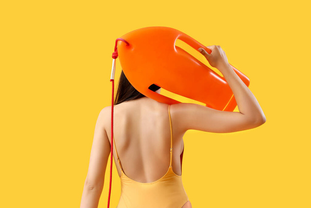 Žena plavčík s prknem na žlutém pozadí, pohled zezadu - Fotografie, Obrázek