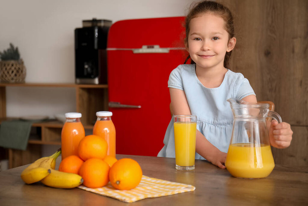 Kleines Mädchen mit Krug und Glas Orangensaft in der Küche - Foto, Bild