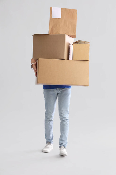 Young courier with parcels on light background - Photo, Image