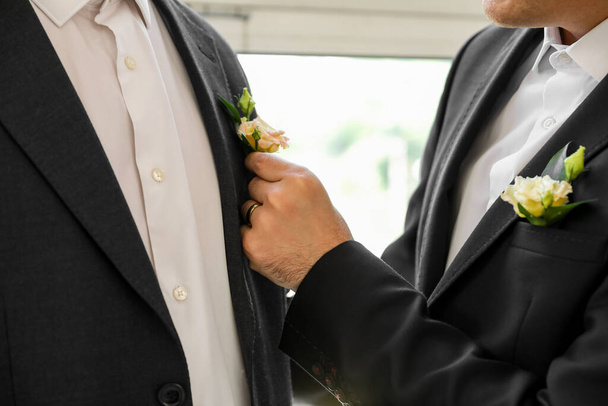 Giovane uomo che fissa boutonniere di suo marito il giorno del loro matrimonio, primo piano - Foto, immagini