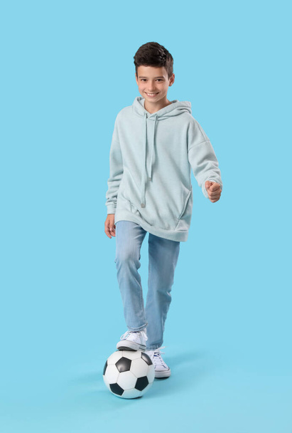 Маленький мальчик с футбольным мячом на синем фоне - Фото, изображение