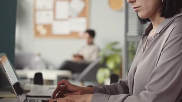 Inclinado hacia arriba de joven hermosa mujer de Oriente Medio escribiendo en el ordenador portátil mientras trabaja en la oficina moderna - Imágenes, Vídeo