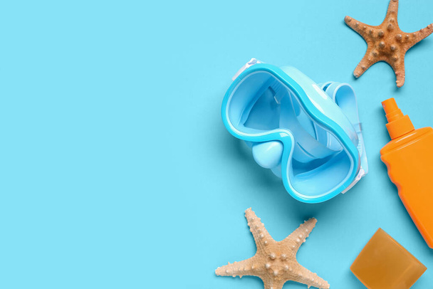 Νέα μάσκα κολύμβησης, αστερίας και μπουκάλι αντηλιακό σε μπλε φόντο - Φωτογραφία, εικόνα