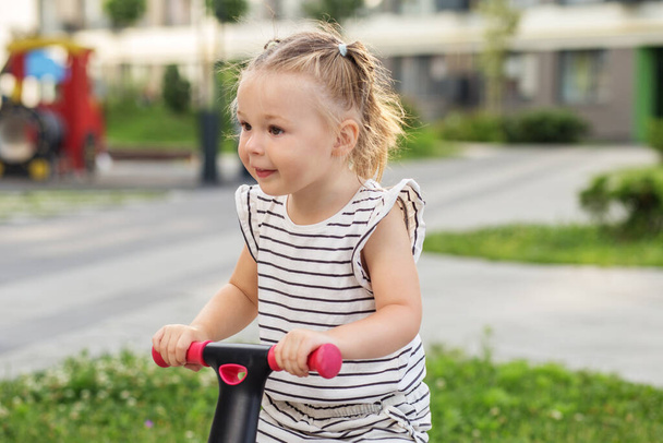 Toddler girl driving balance bike outdoors. Learning to ride bike concept. Urban. - Photo, Image