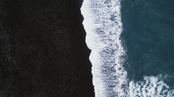 Izlandi fekete homokos strand légi kilátás, látványos Atlanti-óceán partján hullámok zuhannak le a tengerparton. Sarkvidéki táj havas hegyekkel és fekete homokkal a strandokon, hideg táj. Lassú mozgás.. - Fotó, kép