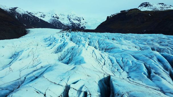 Drónlövedék jeges gleccserblokkokból a vatnajokull jégtömegen Iszkanderben, megrepedt jégsziklák. Fantasztikus jéghegyek és fagyos barlangok látványos sarkvidéki tájat teremtenek. Lassú mozgás.. - Fotó, kép