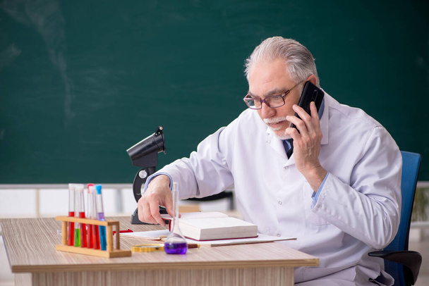 Vanha kemisti opettaja istuu luokkahuoneessa - Valokuva, kuva