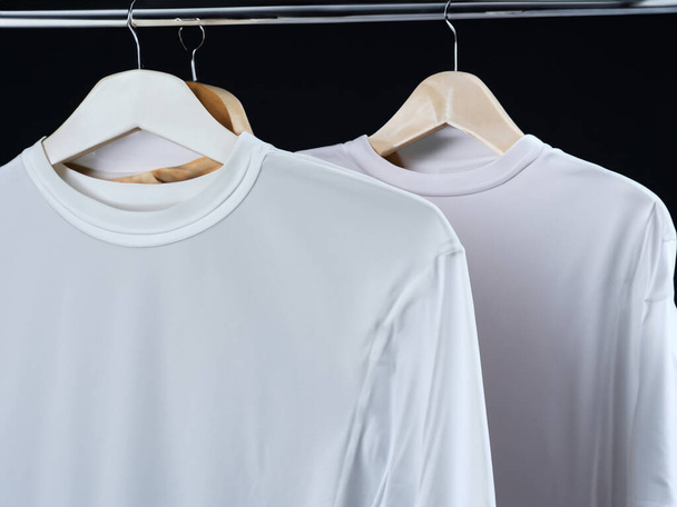 Realistische T-Shirt-Attrappe | Blankes schwarzes und weißes T-Shirt auf Kleiderbügel, Design-Attrappe. Klare T-Shirt-Attrappe aus einfacher Baumwolle. Bekleidungsgeschäft logo mock branding display - Foto, Bild