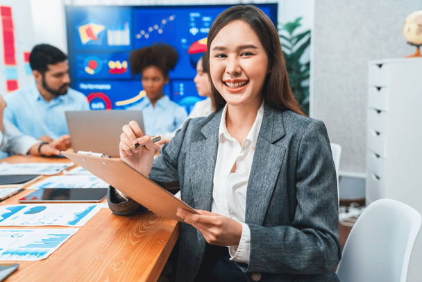 Portrait of happy young asian businesswoman with group of office worker on meeting with screen display business dashboard in background. Confident office lady at team meeting. Concord - Photo, Image