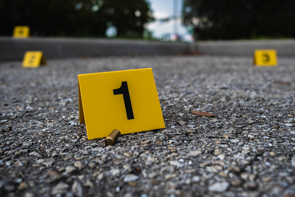 Um grupo de marcadores de evidência de cena de crime amarelo na rua depois de uma arma disparando cartucho de bala de latão carabina - Foto, Imagem