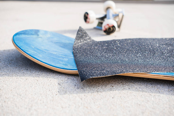 Aplicando fita adesiva a um novo deck de skate ao lado de um conjunto de caminhões e rodas - Foto, Imagem