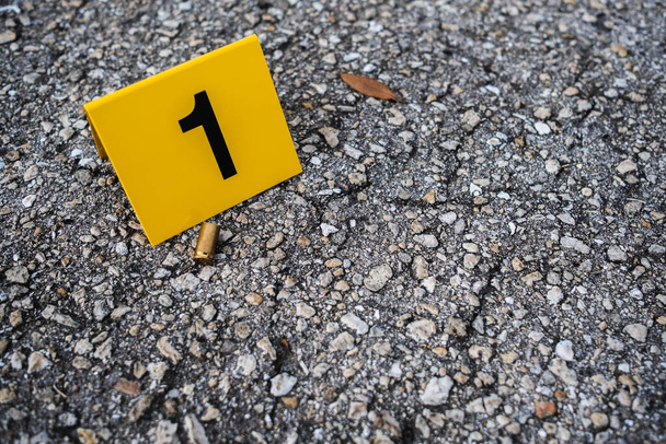 Один жёлтый маркер с места преступления на улице после выстрела из латунной пули в гильзу из пистолета калибра 9 мм - Фото, изображение