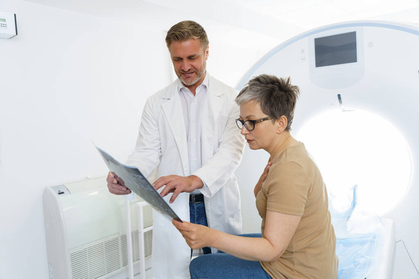 Médico varón explicando resultado de rayos X para paciente mujer enferma en el hospital. Foto de alta calidad - Foto, imagen
