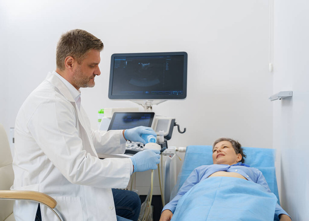 Ultraäänilaitteeseen geeliä levittävä ultraäänitutkimus ennen potilaan hoitoa. Laadukas kuva - Valokuva, kuva