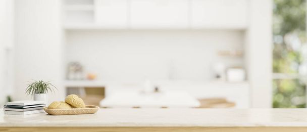Copie el espacio para mostrar su producto en una mesa blanca con una cesta de pan, libros y florero sobre una cocina blanca moderna borrosa en el fondo. 3d render, ilustración 3d - Foto, imagen
