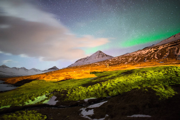 De Aurora Borealis over de bergketen van Stodvarfjordur stad in Oost-IJsland. - Foto, afbeelding