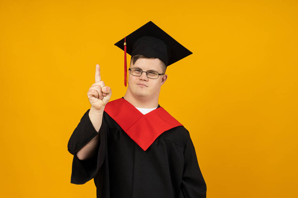 Smiling young man with cerebral palsy wearing glasses in a graduate suit. World Genetic Diseases Day concept - Photo, Image