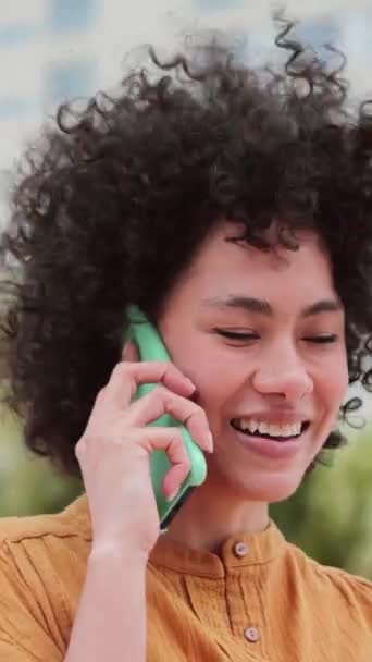 Verticaal individu close-up portret van gelukkige Spaanse vrouw die een gesprek met behulp van een smartphone. Vooraanzicht van een vrolijke Latijnse vrouw opgewonden pratend op een telefoongesprek. Hoge kwaliteit beeldmateriaal - Video