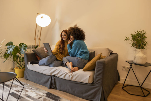 duas mulheres lésbicas casal no sofá em casa assistindo filme no tablet digital - amigos internet mídias sociais - - Foto, Imagem