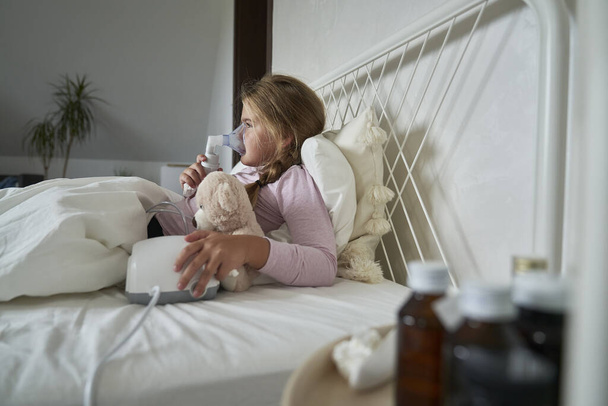 Девочка младшего возраста использует туманность в постели дома - Фото, изображение