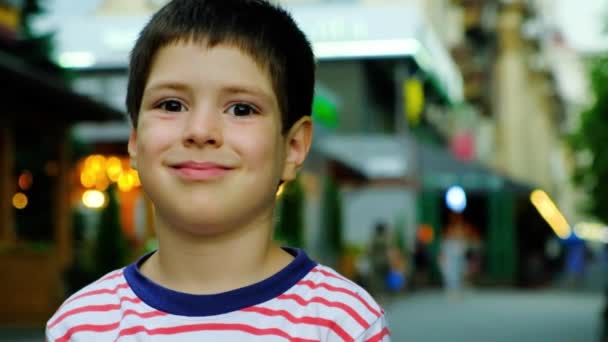 Een portret van een zesjarige jongen die glimlacht en naar de zijkant en naar de camera kijkt. - Video