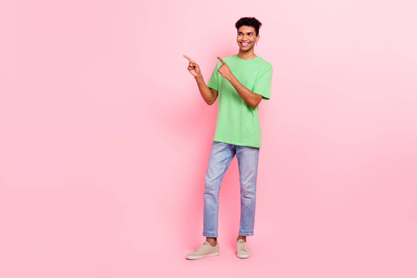 Full length photo of handsome man dressed stylish t-shirt look directing empty space proposition isolated on pink color background. - Фото, изображение