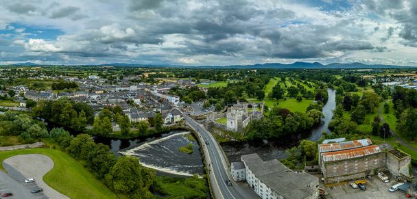 タワーハウス,外の城,円形,長方形のタワー,バンケットホール,滝とゴルフコースでスエア川を渡るのを守るアイルランドの城と町の空中ビュー - 写真・画像