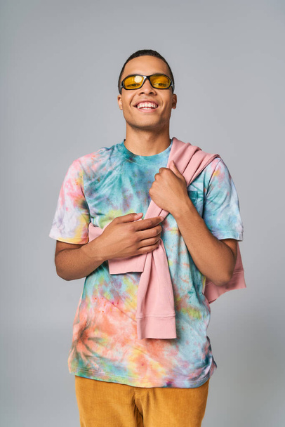 boldog afro-amerikai férfi napszemüvegben és nyakkendő-festék pólóban nézi a kamerát szürke - Fotó, kép