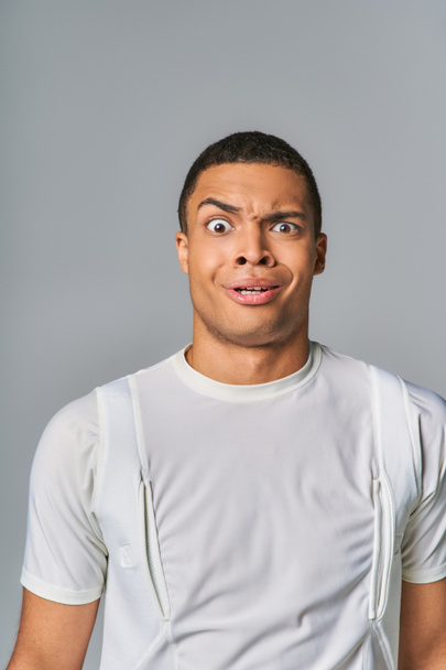 surprised and discouraged african american in stylish t-shirt looking at camera on grey - Fotoğraf, Görsel