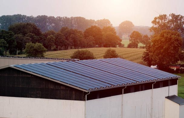 Entrepôt avec panneaux solaires sur le toit. Énergie produite par la nature. Énergie produite par le soleil. Systèmes photovoltaïques sur la maison de grange dans la campagne. Technologie des semi-conducteurs. Empreinte carbone. - Photo, image