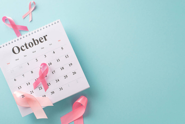 Elementi essenziali della campagna di sensibilizzazione sul cancro al seno. Vista dall'alto scatto del calendario di ottobre, e nastri rosa su sfondo blu pastello. Ottimale per il marketing medico - Foto, immagini