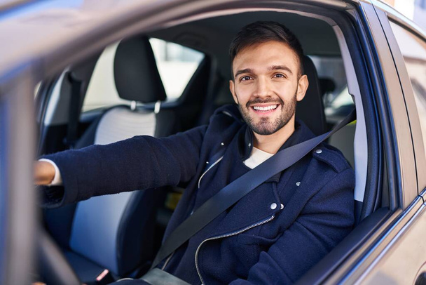 Молодий іспаномовний чоловік посміхається впевнено водити машину на вулиці
 - Фото, зображення