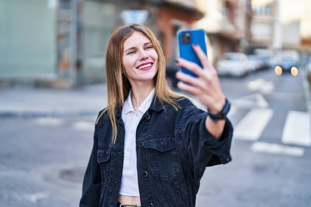 Young blonde woman smiling confident making selfie by the smartphone at street - Photo, image