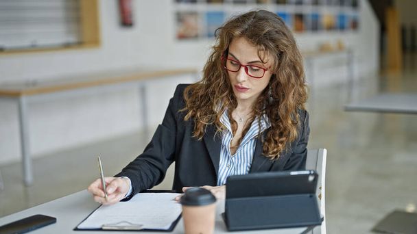 Молодая деловая женщина с помощью тачпада пишет на документе в офисе - Фото, изображение