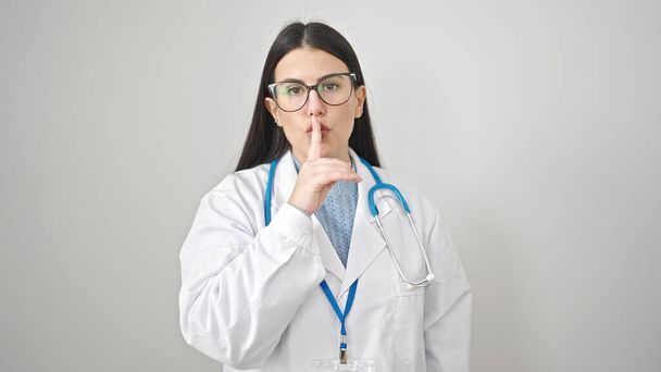 Νεαρή Ισπανίδα γιατρός ζητάει ησυχία σε απομονωμένο λευκό φόντο. - Φωτογραφία, εικόνα