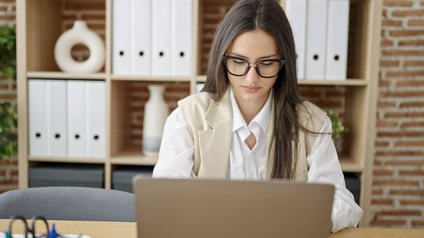 Молода красива іспанська жінка бізнесмен, використовуючи ноутбук, що працює в офісі
 - Фото, зображення