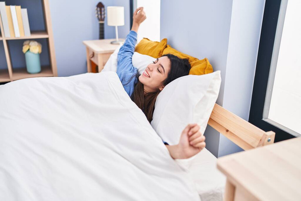 Genç, güzel İspanyol bir kadın yatak odasında kollarını açarak uyanıyor. - Fotoğraf, Görsel