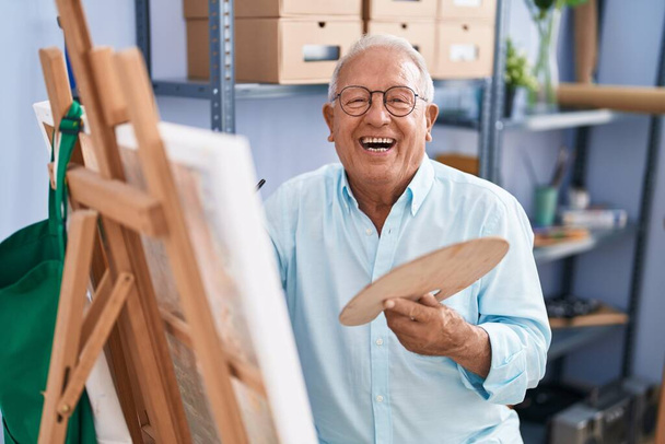 Senior grey-haired man artist smiling confident drawing at art studio - Photo, Image