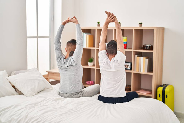 Two men couple waking up stretching arms at bedroom - Fotó, kép