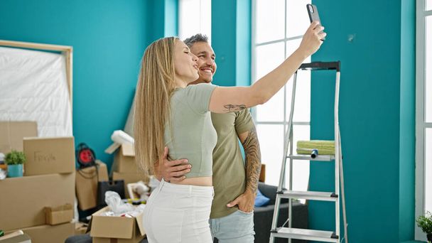 男と女カップルは,新しい家でビデオ通話を持っているお互いに抱擁 - 写真・画像