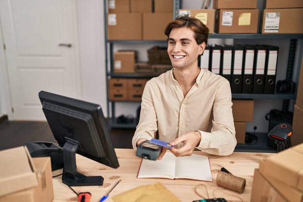 Молодий кавказький чоловік електронної комерції бізнесмен використовує дані телефон і кредитну картку в офісі
 - Фото, зображення