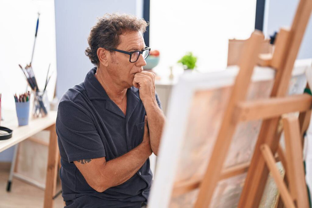 Keski-ikäinen mies taiteilija etsii piirtää epäilevästi ilmaisun taidestudio - Valokuva, kuva