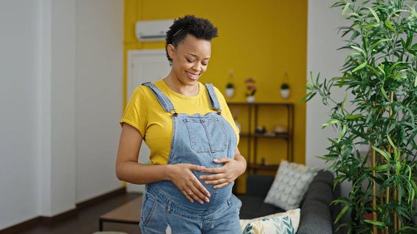Young pregnant woman smiling confident touching belly at home - Valokuva, kuva