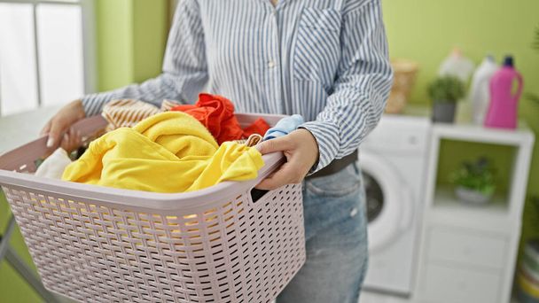 Mujer joven sosteniendo cesta con ropa en la lavandería - Foto, imagen
