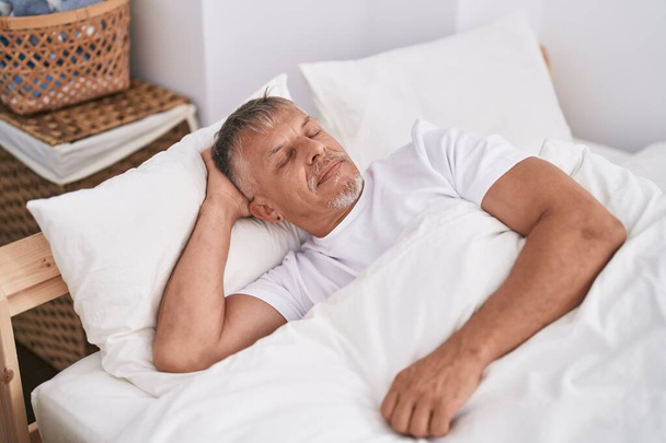 Middle age grey-haired man lying on bed sleeping at bedroom - Photo, Image
