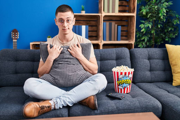 Junger Mann, der Popcorn isst, ist skeptisch und nervös und runzelt ob des Problems die Stirn. negative person.  - Foto, Bild