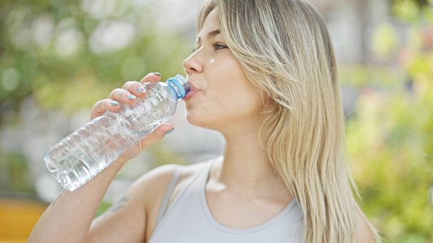 Mujer rubia joven bebiendo agua en el parque - Foto, Imagen