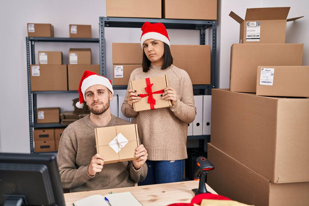 Zwei junge Leute, die zu Weihnachten im E-Commerce eines Kleinunternehmens arbeiten, entspannten sich mit ernstem Gesichtsausdruck. einfacher und natürlicher Blick auf die Kamera.  - Foto, Bild